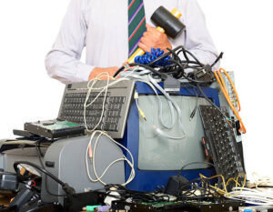 man holding hammer behind a stack of computer equipment to recycle.Blurred background.